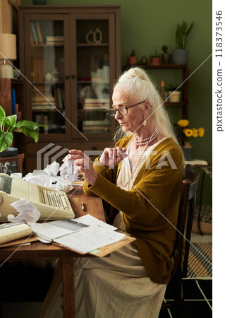 Concentrating Senior Woman Working on Typewriter in Office 118373546