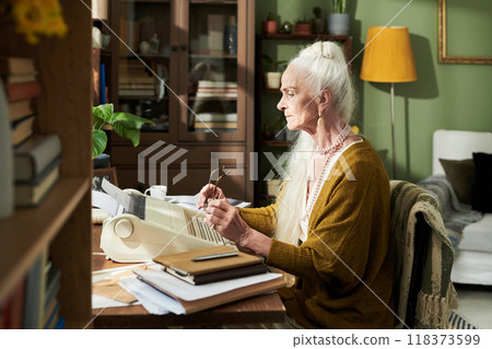 Elderly Woman Typing on Typewriter in Home Office 118373599