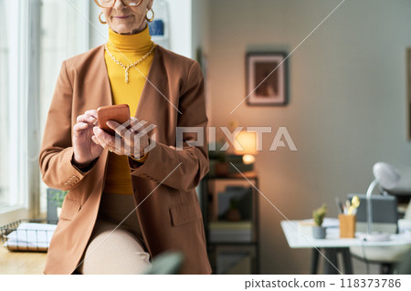 Elderly Woman Using Smartphone in Modern Bright Office Elderly Woman Using Smartphone in Modern Bright Office 118373786