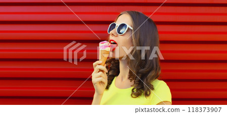 Summer portrait of happy young woman enjoying eating ice cream on red background 118373907