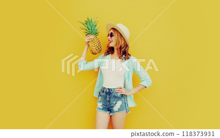 happy smiling woman holding pineapple having fun in summer hat on colorful yellow background 118373931