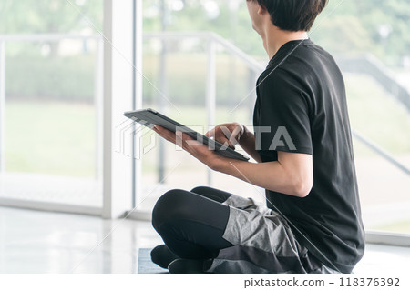 穿著運動服的年輕亞洲男子使用平板電腦設備 118376392