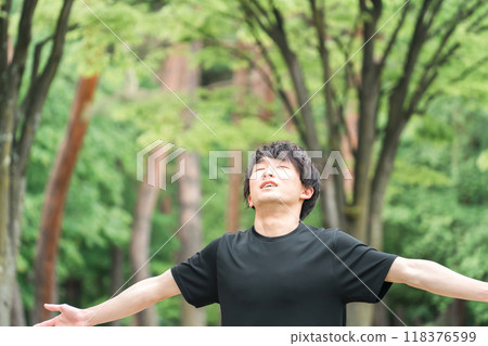 A young man in sportswear taking a deep breath (forest bathing, stress relief, mood change, morning activities, warm-up exercises, sunbathing) 118376599