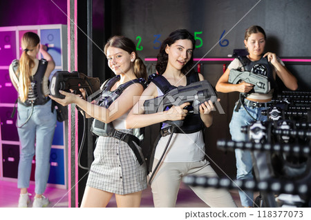 Two cheerful and happy girls friends pose in locker room before laser tag match. Two cheerful and happy girls friends pose in locker room before laser tag match. 118377073