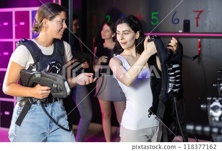 Young women choose protective equipment and uniforms before playing laser tag Young women choose protective equipment and uniforms before playing laser tag 118377162