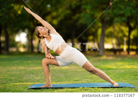 Girl performing Extended Side Angle Pose during yoga practice outdoors 118377167
