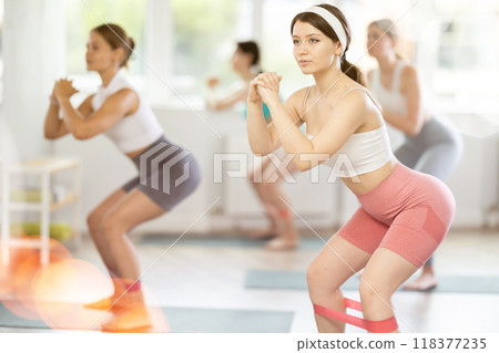 Young girl practicing half squat with band standing on mat 118377235