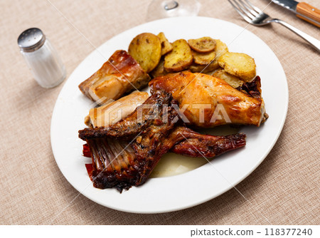 Roasted rabbit pieces with vegetable garnish of fried potatoes 118377240