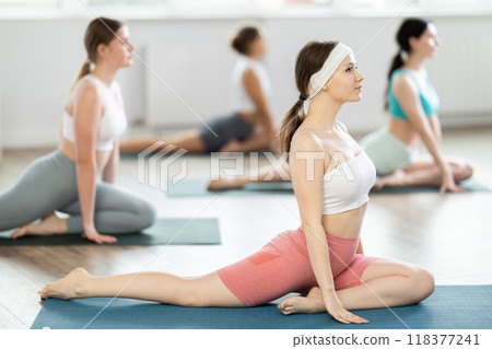 Young girl practicing pigeon pose in pilates studio 118377241