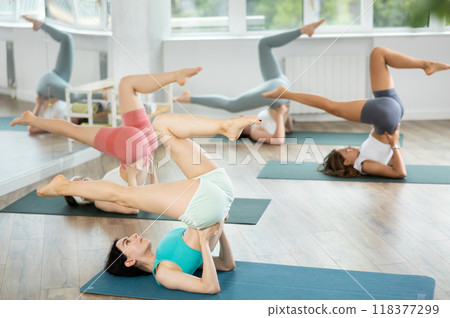 Young girls practicing shoulder stand pose in pilates studio 118377299
