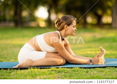 Young woman practicing yoga on green glade in summer park Young woman practicing yoga on green glade in summer park 118377327