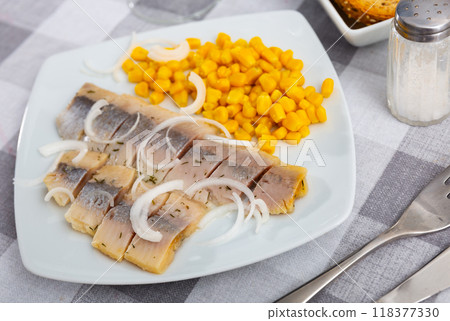 Sliced pickled herring fillet with corn and onions on plate 118377330
