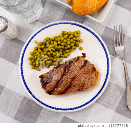 Grilled veal steak with vegetable garnish of canned green peas. Healthy dinner concept 118377338