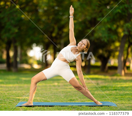 Girl in park on green grass of lawn performs padmasana Girl in park on green grass of lawn performs padmasana 118377379