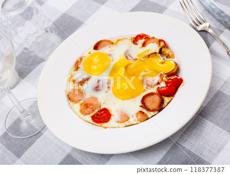 Fried eggs with tomato served with sausage 118377387