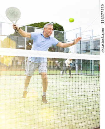 Emotional mature man playing paddle tennis outdoors 118377389