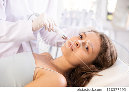 Young woman undergoing cosmetic facial treatment using ion bubble attachment 118377393