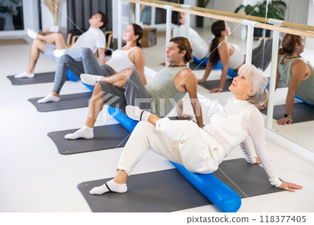 Women and men doing stretching workout during group training in yoga class 118377405