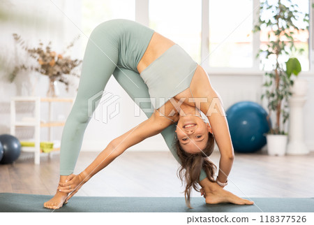 Woman exercising warrior one pose during yoga training in gym Woman exercising warrior one pose during yoga training in gym 118377526