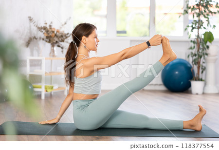 Experienced girl fitness club teacher performs Eka Pada Eka Hasta Salamba Navasana 118377554