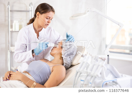 Aesthetician administering facial procedure on young woman using ultrasonic shovel Aesthetician administering facial procedure on young woman using ultrasonic shovel 118377646
