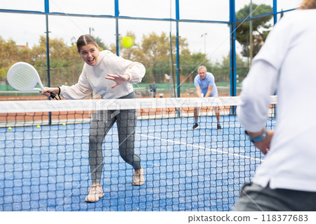 Emotional young European girl padel player hitting ball with racket on hard court in autumn 118377683