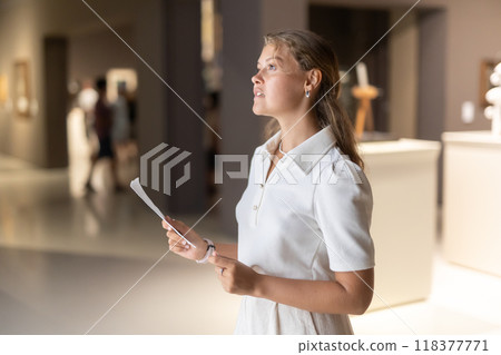 Woman with sheet piece of paper in hands view sculpture in museum hall Woman with sheet piece of paper in hands view sculpture in museum hall 118377771