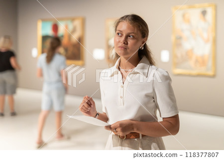 Woman with sheet piece of paper in hands view pictures and icons in museum hall 118377807