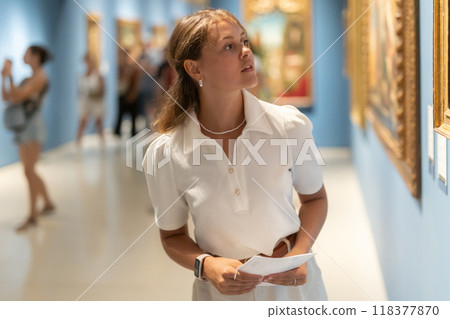 Woman with sheet piece of paper in hands view pictures and icons in museum hall 118377870