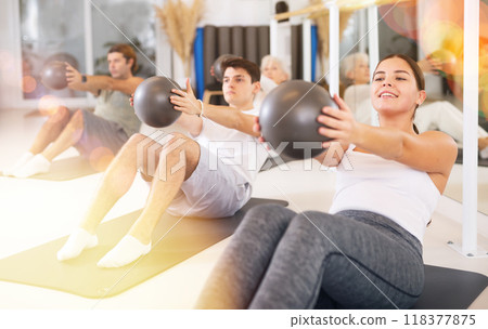 Pilates group workout for a healthy lifestyle. Strong men and women have fun doing sports exercises with ball. 118377875