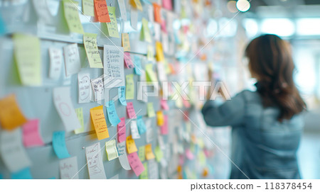 A woman is writing on a whiteboard with colorful sticky notes 118378454