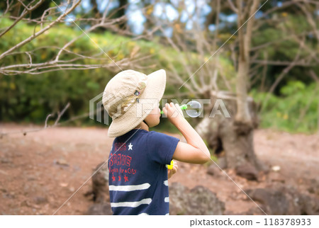 A boy playing with soap bubbles in the park A boy playing with soap bubbles in the park 118378933