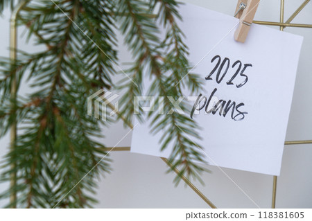 2025 PLANS text on white paper note on vision board with Christmas decor. New year aims resolutions. New me you concept visualizing 2025 PLANS text on white paper note on vision board with Christmas decor. New year aims resolutions. New me you concept visualizing 118381605