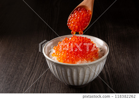 將一些鮭魚子舀到米飯上。 118382262