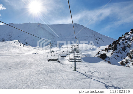 Chunkurchak ski resort in Kyrgyzstan. Empty ski lift seats. Mountain slope at sunny winter day Chunkurchak ski resort in Kyrgyzstan. Empty ski lift seats. Mountain slope at sunny winter day 118382339