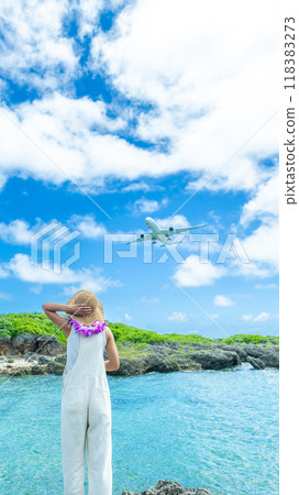 一名婦女抬頭看著一架降落在機場的客機的肖像 118383273