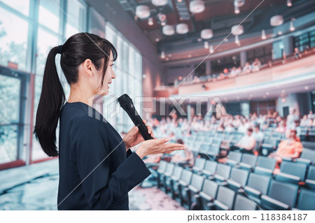 A young woman hosting a meeting in a hall A young woman hosting a meeting in a hall 118384187