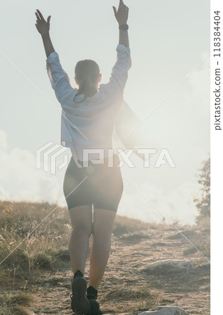 Woman Hiking Mountain Peak Celebrating Success 118384404