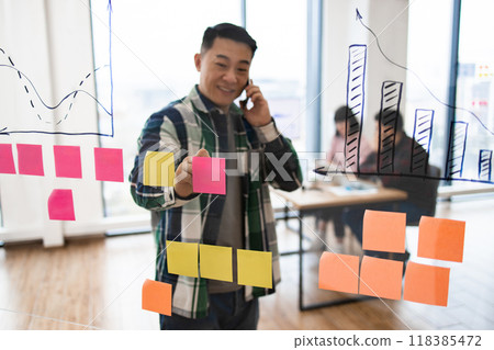 Businessman brainstorming with sticky notes and charts in office 118385472