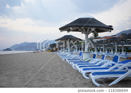 A row of empty deck chairs on a tropical beach. The coast of the Indian Ocean. The concept of recreation. A row of empty deck chairs on a tropical beach. The coast of the Indian Ocean. The concept of recreation. 118386694