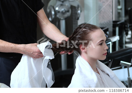 A young woman washes her hair in a beauty salon. Clean wet hair.The hair is dried with a towel. A young woman washes her hair in a beauty salon. Clean wet hair.The hair is dried with a towel. 118386714