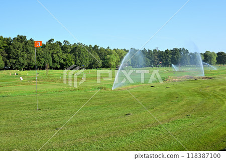 Cool early morning, sprinklers spraying water, park golf course 118387100