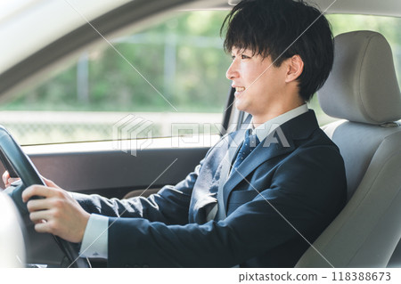 A young male businessman in a suit driving a car 118388673