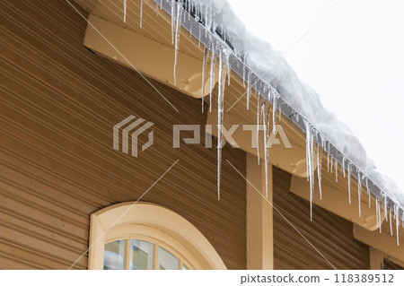 Icicles hang on the roof edge 118389512