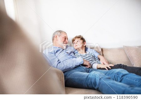 Boy and grandpa relaxing on sofa. Grandfather spending time with grandson, taking care of him while parents are at work. 118390590