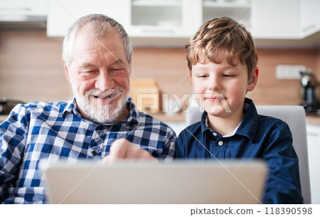 Boy and grandpa making videocall on tablet. Grandfather spending time with grandson, taking care of him while parents are away. Boy and grandpa making videocall on tablet. Grandfather spending time with grandson, taking care of him while parents are away. 118390598