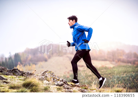 Male runner jogging in nature on dirt running trail. Morning running training for young man. 118390655