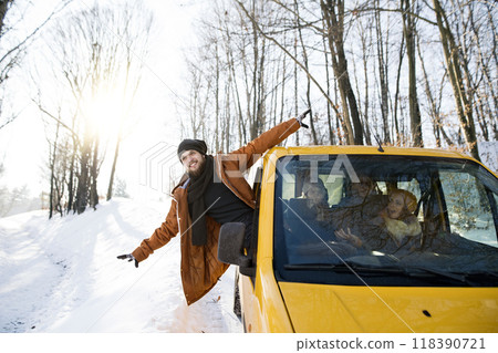 Friends traveling by car on winter holiday, spending Christmas in cabin. Driving through snowy landscape. 118390721