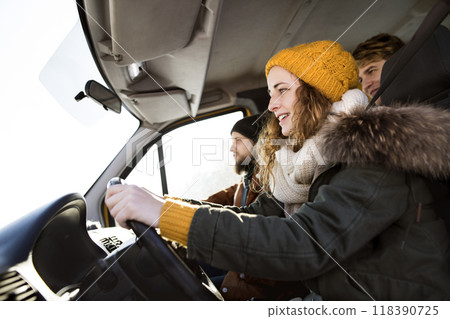 Friends traveling by car on winter holiday, spending Christmas in cabin. Driving through snowy landscape. 118390725
