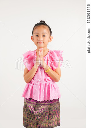 Portrait of Thailand kid girl smiling traditional Thai dress costume posing to pay respect in studio shot isolated white background, Happy kindergarten child sawasdee symbol or welcome 118391336
